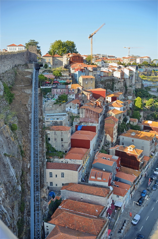 17 - The Guindais Funicular running alongside the medieval Fernandine Walls on a steep cliffside overlooking the historic tiered rooftops and the Ribeira district in Porto